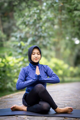 Healthy Asian woman in sportswear do yoga at the park. Moslem woman with sportwear.