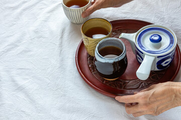 お盆に乗せたお茶の入った湯飲み