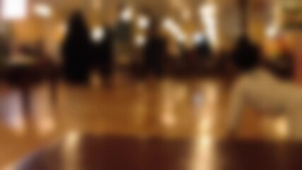Bokeh view of people walking on the cozy place at night. Concept of blurred crowd peoples background footage.