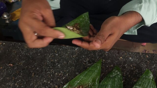 Preparation paan combining betel leaf with betel nut or areca nut. A traditional Indian delicacy, betel leaf with a variety of sweet and savory ingredients before folding it into a chewable bite. 