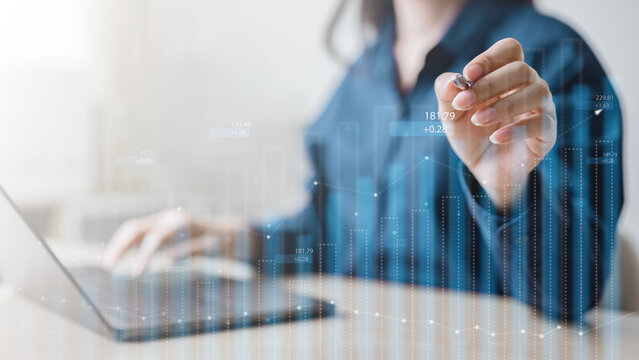 Businesswoman analyzing financial data with laptop and digital chart overlay, symbolizing investment strategy, stock trading, and modern business finance solutions.