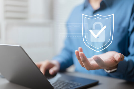 Businessman using laptop with digital shield and check mark icon, symbolizing cybersecurity, data protection, online privacy, and secure access in modern technology.