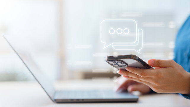 Close-up of a person using smartphone with chat icon overlay, symbolizing online communication, social media messaging, and modern digital interaction.
