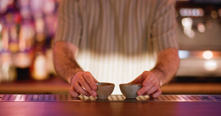 Sake cup. Serving alcoholic drink. Barkeeper putting on counter little empty clay bowls for traditional asian beverage. Ceramic dishes for rice wine.