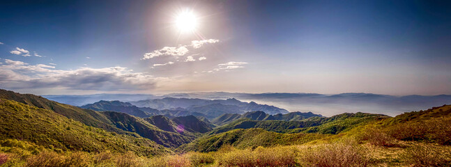 Vibrant sunset and sunrise panoramas over mountain landscapes with a cloud-covered sky and green forests © Pan