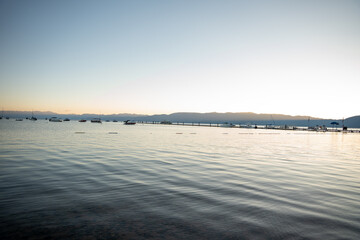 Obraz premium Sunrise over South Lake Tahoe, calm waters andboats