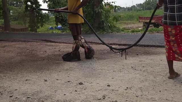 Road construction works going on in slow otion. Indian men working road maintenance. Road construction site in India. Road construction works going on in slow motion. Indian worker spraying primer.