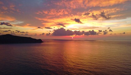 Fiery sunset over tranquil ocean and distant land