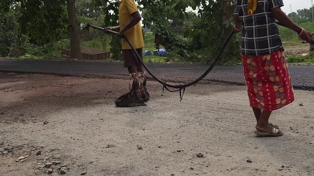 Road construction works going on in slow otion. Indian men working road maintenance. Road construction site in India. Road construction works going on in slow motion. Indian worker spraying primer.