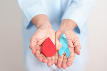 Elderly woman with Blue ribbon and red Blood drop for World Diabetes Day, Blue November Health,...