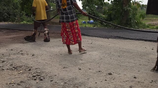 Road construction works going on in slow otion. Indian men working road maintenance. Road construction site in India. Road construction works going on in slow motion. Indian worker spraying primer.