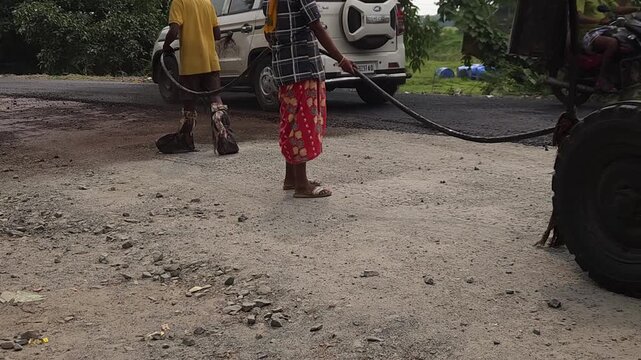 Road construction works going on in slow otion. Indian men working road maintenance. Road construction site in India. Road construction works going on in slow motion. Indian worker spraying primer.