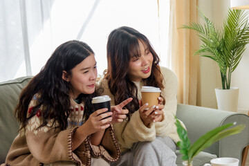 Winter day, women friends cherish home friendship, enjoying warm beverages, sharing cheerful conversation, wearing comfortable sweaters for cozy winter evening relaxation