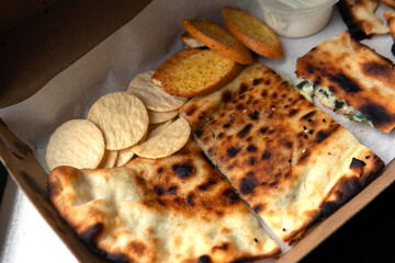 Light meal party set for celebration Fresh gozleme stuffed with crackers restaurant ordered takeaway in eco environmental friendly recycled cardboard box brown paper packaging with yoghurt dip