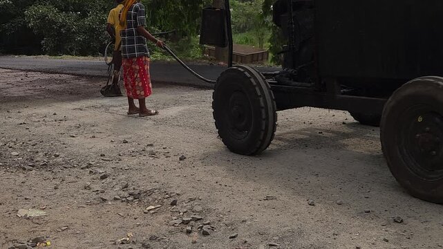 Road construction works going on in slow otion. Indian men working road maintenance. Road construction site in India. Road construction works going on in slow motion. Indian worker spraying primer.