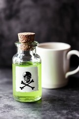 Dark background with small vial, green liquid, poison skull label, and tea vial cork liquid