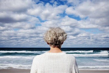Fototapeta premium Elderly woman enjoying herself at the beach with a view from behind. Back