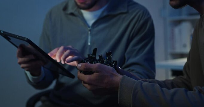 Team adult male engineer collaborate on robotic hand project using AI code solutions machine learning at tech workspace night. Artificial intelligence interface, collaboration prototype development.