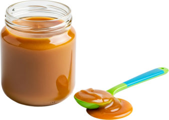 A jar of sweet caramel sauce next to a spoonful of the thick golden liquid with a colorful spoon isolate
