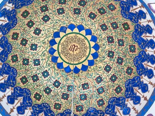 Close-up view of the dome’s center, showing vibrant blue, green, and gold motifs with Arabic calligraphy in the middle.