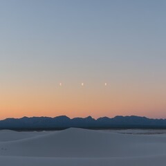 Fototapeta premium Surreal Triple Moonrise Over White Sand Dunes and Mountains at Dusk