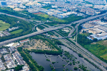 Urban expressways intersect through green landscapes and calm waterways, forming a dynamic view of infrastructure blending with nature, symbolizing modern city growth and connection.