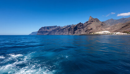 Rocky mountain coastline with deep blue ocean water and clear sky on sunny day, peaceful and scenic view