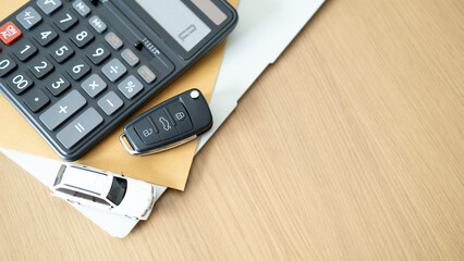 Black car key with calculator and toy car on wooden desk concept for auto finance loan installment...