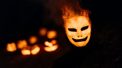 Flaming pumpkin mask with sinister smile, glowing in darkness, surrounded by jack o lanterns, evokes eerie Halloween atmosphere