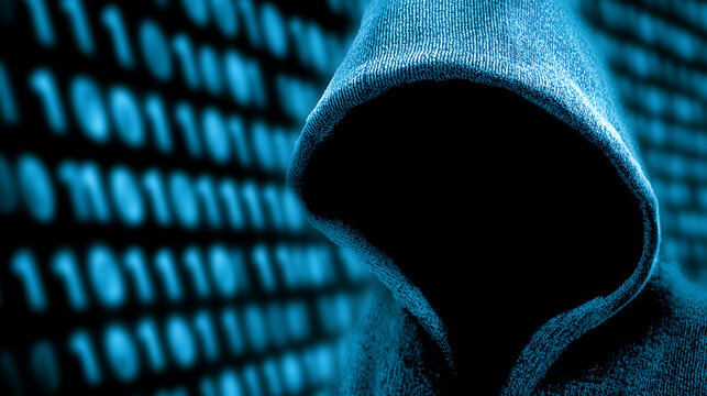 Silhouetted figure in a hooded sweatshirt against a background of binary code, suggesting cybercrime or digital anonymity.