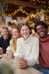 group of friends laughing together in cozy canadian caf adorned with twinkling fairy lights