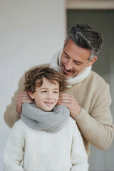 father gently helps his child tie scarf showcasing warmth and care in their bond