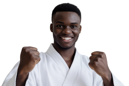 Young black man in karate gi smiling with fists raised isolated on transparent background. Male black african taekwondo practitioner smiling with raised fists isolated on white background.