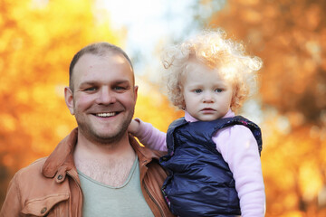 Girl walking in the autumn park. Autumn in the city, girl with dad for a walk. Parents are walking with little children. Autumn park people