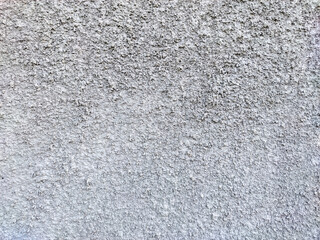 A textured close-up of a gray concrete wall with a rough, stucco-like finish. The uneven surface is a mix of light and dark gray tones, creating a durable, industrial aesthetic