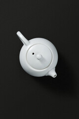 White ceramic teapot on a dark textured background