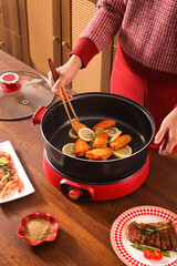 Woman Cooking Delicious Chicken Wings in a Modern Electric Skillet
