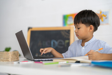 Asian boy using laptop with course online learning, distance education for kids, e-learning at...