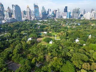 Obraz premium Aerial view green tree forest Lumpini public park with modern office building agiant blue sky cloud
