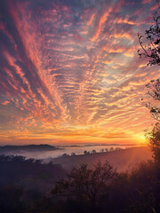 vibrant dramatic sunrise sunset misty mountainous hilly landscape colorful sky orange red yellow blue purple clouds rolling hills fog ethereal atmosphere silhouettes trees serene natural scenery