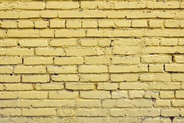 Fototapeta premium A textured yellow brick wall showing mortar lines and slight color variations