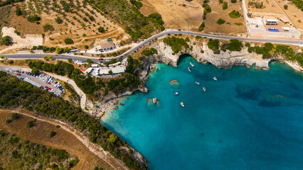 Zakynthos Greece Makris Gialos beach top view of clear blue sea rocky coastline boats floating near cliffs and dry hillside landscape with road