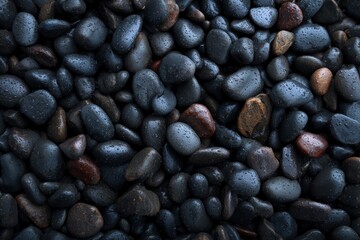 Pile of dark river rocks wet with raindrops showing subtle variations in color