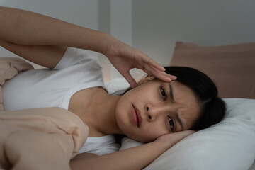 asian woman in bed late trying to sleep suffering insomnia, sleepless or scared in a nightmare, looking sad worried and stressed. Tired and headache or migraine waking up in the middle of the night.