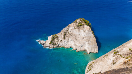Aerial view of Plakaki beach Zakynthos Greece coastline with rugged cliffs turquoise shallows deep blue Ionian Sea and rocky formations nearby