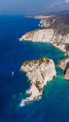 Aerial view of Plakaki beach Zakynthos Greece with tall cliffs turquoise shallow sea rocky coastline and dramatic barren hills above the coast