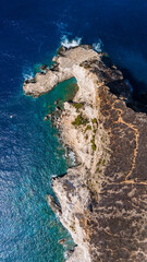 Plakaki beach Zakynthos Greece top down aerial showing dramatic rocky headland turquoise shallow waters and deep blue sea surrounding coastline