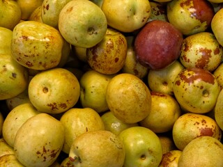 A full frame, close-up shot of a large pile of fresh jujube fruits (Chinese dates). 