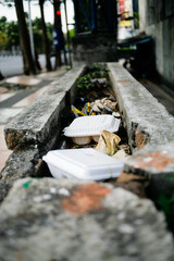 discarded disposable styrofoam lunch box on drainage