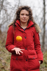 A girl in a red jacket throws an orange